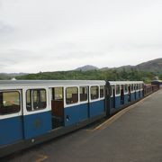 横に２人しか座れない小さな列車を蒸気機関車がけん引する鉄道