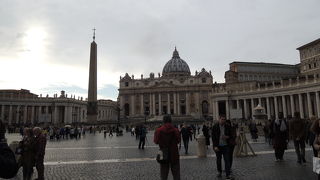 中心にオベリスク、サンピエトロ大聖堂と巨大な柱の回廊、広場の前には店舗がいっぱい