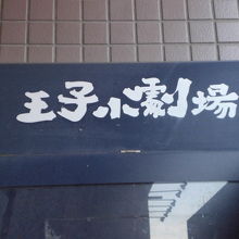 建物の壁に掲げられている花まる学習会王子小劇場の標識です。