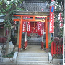 装束稲荷神社の鳥居と社殿です。左側に由緒を記した解説があり。