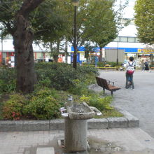 柳田公園の水飲み場や植栽です。茶色のベンチも置かれています。
