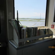 車窓の田んぼと菜の花、遠くに岩木山 