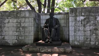 杖を持ち椅子に座っている像