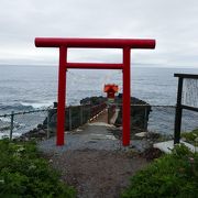 海に突き出た岩に朱色の祠が