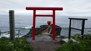 海に突き出た岩に朱色の祠が