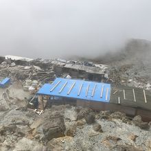 火山岩の直撃の穴が残る解体中の山頂小屋