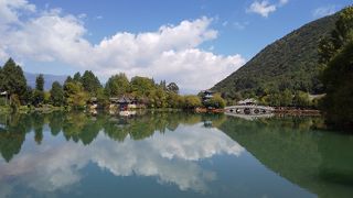 白い雲と緑の山と玉龍雪山の山影を水面に映す黒龍潭です。