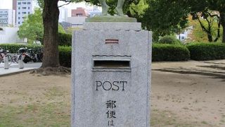 二人の子供が手をつないだブロンズ像が載っているポスト