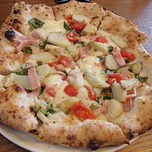 じゃがいも・ベーコン・プチトマト等がトッピングされたピザ