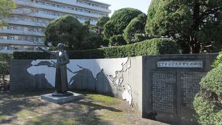 右手を斜め前に揚げ、後ろには世界地図が描かれていました。