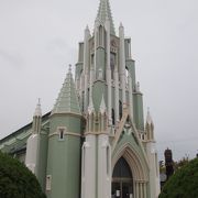 美しい薄緑色の教会で十字架を掲げた白い像ザビエル像が立っています。