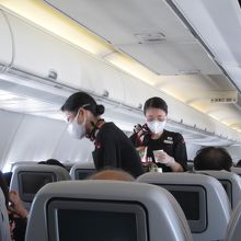 ドリンクを配布するＣＡ。アイガード、マスク、ビニ手姿です。