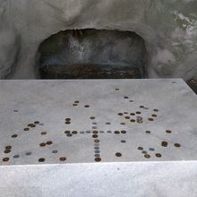 洞窟に置かれた台にコインの十字架