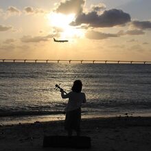 飛行機を見ながら三線を弾く人み～つけた