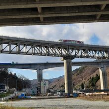 安家川橋梁通過中の三陸鉄道車両。画像奥は建設途中の三陸沿岸道