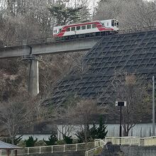 まついそ公園脇の崖の中腹にある鉄橋を三陸鉄道の車両が通過中。