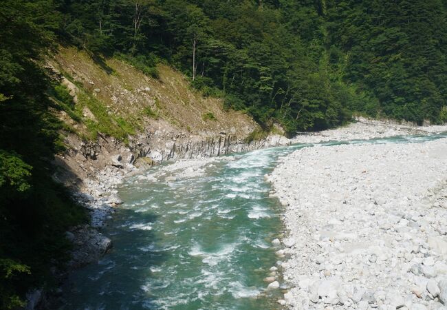 視界が開けた河原と山際に沿って流れる青い水の流れ