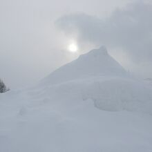 弱弱しい冬の太陽が巨大な雪山の背後に望めました…。