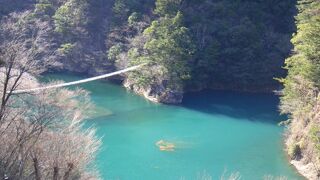 エメラルドグリーンの川にかかる綺麗な吊橋