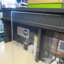 アクリル板の仕切りとマスク着用の案内あり。