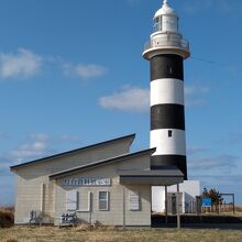 白黒デザインの灯台。手前には小さな資料館がある