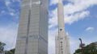 民家の合間に見えて来るH-2ロケットの実物大模型とスペースタワーがシュール