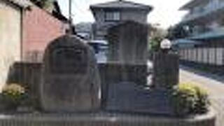 住宅街の駐車場前に駒札が建っています