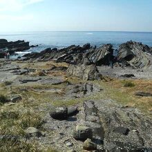 水平線をバックに荒い岩場が広々と続いてる中、海岸散歩