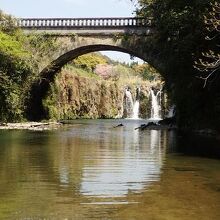 橋が川面に写って丸、後ろに滝が見えます