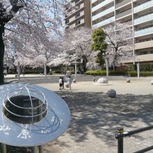 北原公園の標識の背後には、桜の樹が映え、階段と広場が見えます