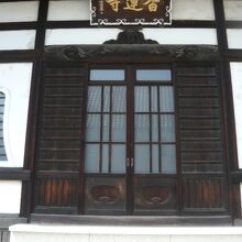 香蓮寺の本堂の様子で､白壁を背景とする茶褐色の扉が印象的です