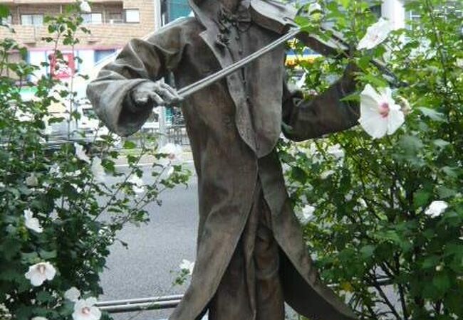 街の音楽の銅像は、青山通りとスタジアム通りの交差点の横断跨線橋のすぐ傍にあります。