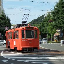 オレンジ色の電車が道路の真ん中を走っています