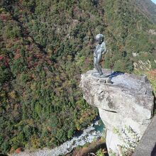 断崖絶壁に付き出した岩の上にある小便小僧の像