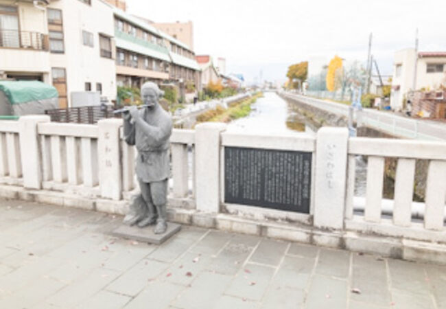橋の上に笛吹権三郎さんの銅像があります
