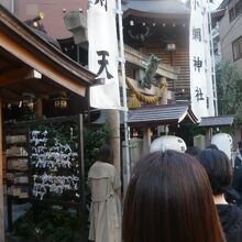 小網神社の入口の前に並ぶ人たち。幟のある入口まで、長い列が。