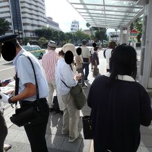 バス停で車掌による改札、運賃回収が行われる
