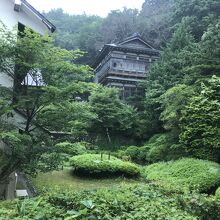 部屋の窓から中庭の中に建つ御殿を見る