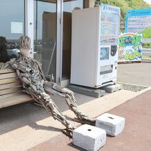 道の駅前のベンチに座る流木アートの人形ｗ 