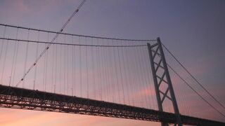 海上から眺める夕日に映える明石海峡大橋