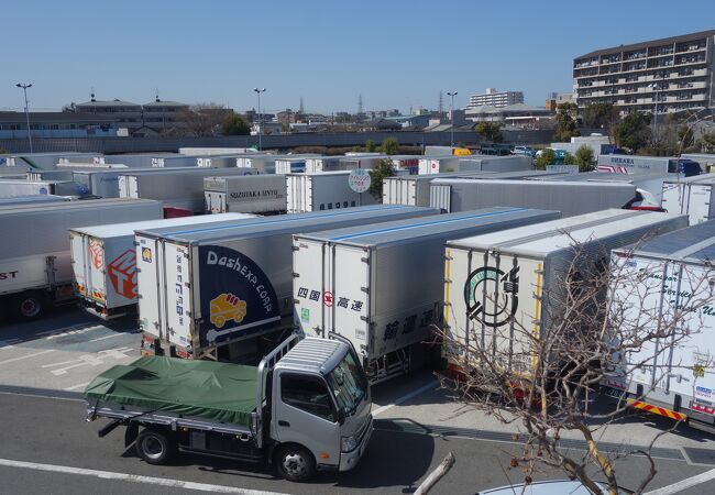 多くのトラックが並んでとまっていて，エンジンをかけて，運転手が休憩している。