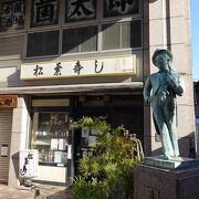 お寿司屋さんの前に小さなブロンズ像があります