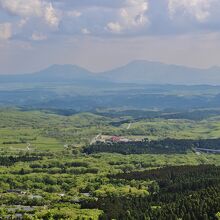 牧ノ戸峠を超えると眼下に瀬の本高原を一望。背後は阿蘇山