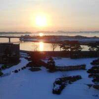 雪の庭園の先に松島湾の海。そこに日が昇りました。