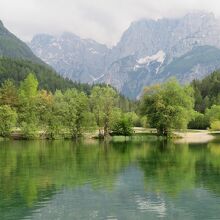 トリグラフ山（画像奥右寄り）などの山々や木々の倒影が美しい湖