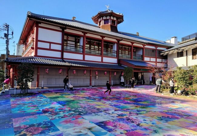 飛鳥時代の建物を模した新しい温泉施設、施設前の広場には一面カラフルなアート作品が描かれています。