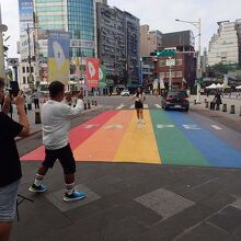 虹が描かれた路面で撮影をする若者たち