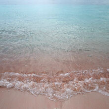 沖の船、ブルーグリーンの海、ピンクの浜辺が幻想的。