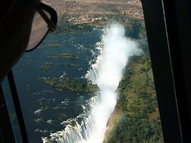 ビクトリアの滝はナイヤガラの滝、イグアスの滝と並び世界三大瀑布の一つ。世界遺産にも登録されている。英国人のデビット・リビングストンにより１８５５年発見された。アンゴラの奥地に水源を持つ。ジンバブエとザンビアの国境線にもなっている。ビクトリアフォルズと呼ばれているが、現地名は「モシ・オヤ・ツンヤ」といわれ「雷鳴の轟く水煙」という意味である。その名の通り水煙が凄い！風の向きによっては遊歩道は夕立の土砂降りの中を歩いているくらいである。最大滝幅1,700m、落差108mの規模を誇る。私の感じでは南米のイグアスの滝には及ばない。見る順序を間違えないように・・ <br /><br />詳細は<br />http://yoshiokan.5.pro.tok2.com/<br />旅いつまでも・・★画像 旅行記<br /><br />をご覧下さい。<br /><br /><br />本文は　<br />http://yoshiokan.5.pro.tok2.com/nana/nori140nana.html<br />ジンバブエの旅をご覧下さい。