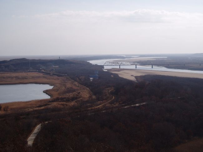 この写真は琿春市の防川にある三国国境地帯です。琿春市は人口約２２万人、そのうち朝鮮族は４２．３％を占めています。ここから日本海までは１５ｋｍ、中国が日本海にでる唯一の道となっています。写真左に見えるのがロシア側ハサン、川を挟んで右側が北朝鮮の豆満江市です。この地域は東北のゴールデントライアングルと呼ばれています。<br /><br />ロシア側との経済合作計画。主に次の三期に分けられます。<br />第一期　２００２年−２００５年　防川、ハサンを開発し、小範囲の国際経済合作区を形成<br />第二期　２００５年−２００８年　琿春、ウラジオストク、ポシェットを開発し、やや広域の国際経済合作区を形成<br />第三期　２００８年−２０１２年　琿春全域、ハサン全域を開発、発展させた広範囲の国際経済合作区を形成<br />現在は第二期に入ったところです。<br />　<br />これまで私は１９９５年３月、２００３年９月、２００４年５月、この写真を撮った２００４年１１月で計４回訪問していますが、来るたびに施設、道路等が新しくなっています。<br /><br />この時の訪問が縁で、その後家族で５年以上延辺に住むようになるとは誰が予想できたことでしょう。人生本当にわからないものです。